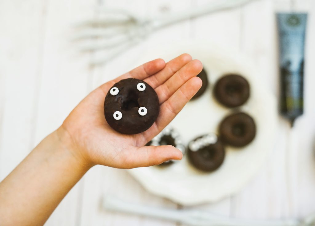 Chocolate donut in a hand with candy eyes