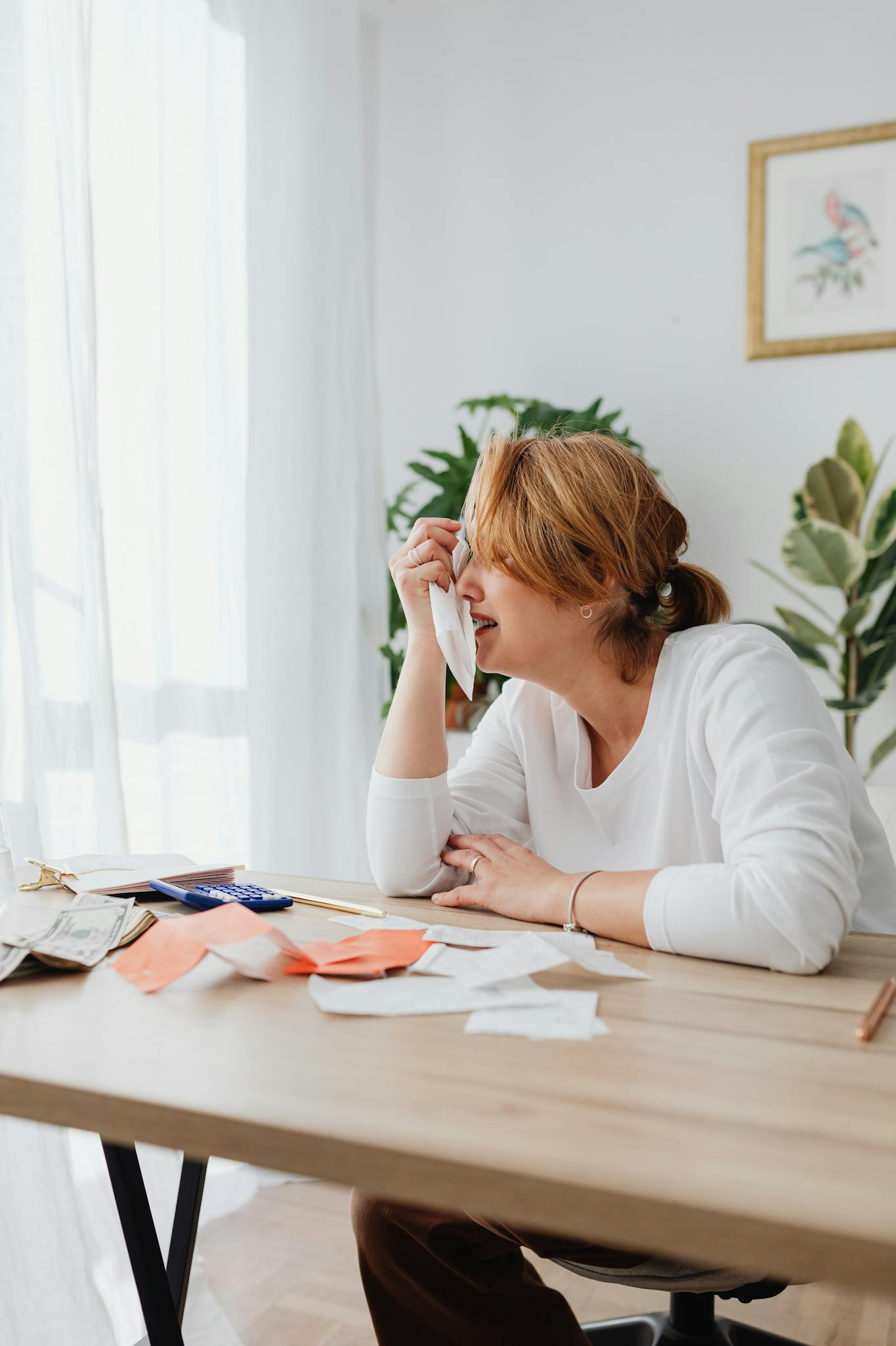 A woman sits at a desk, looking worried with receipts scattered around. Perfect for financial stress themes.