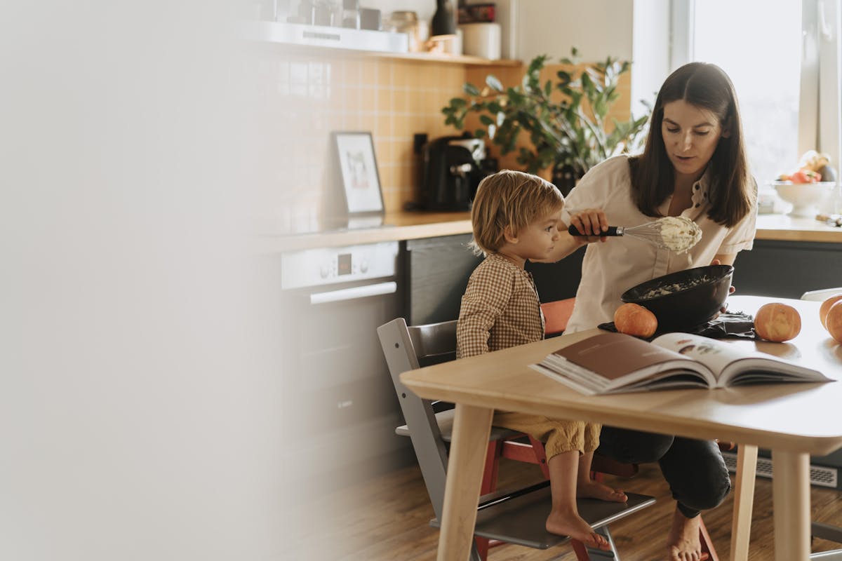A mom and her child baking in a cozy kitchen surrounded by pumpkins.