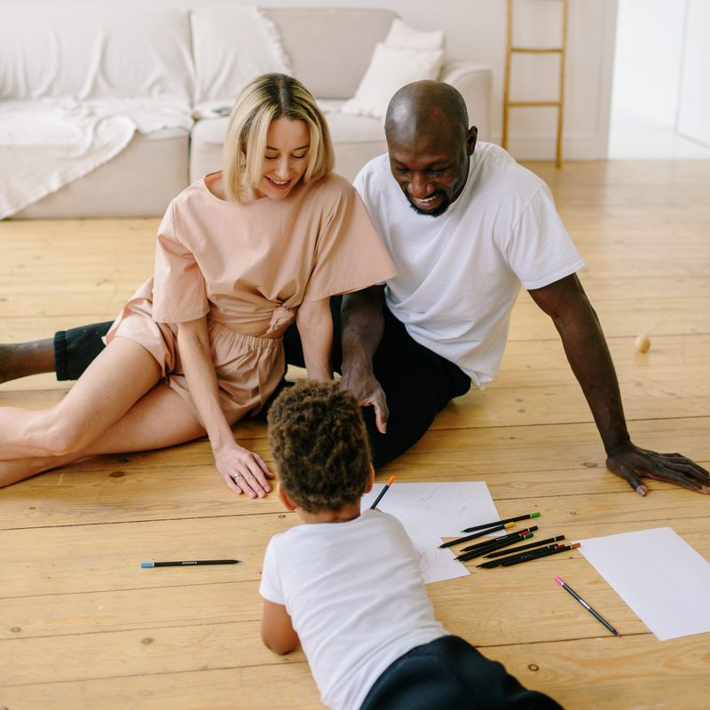 Happy family enjoying drawing together at home with art materials and colored pencils.