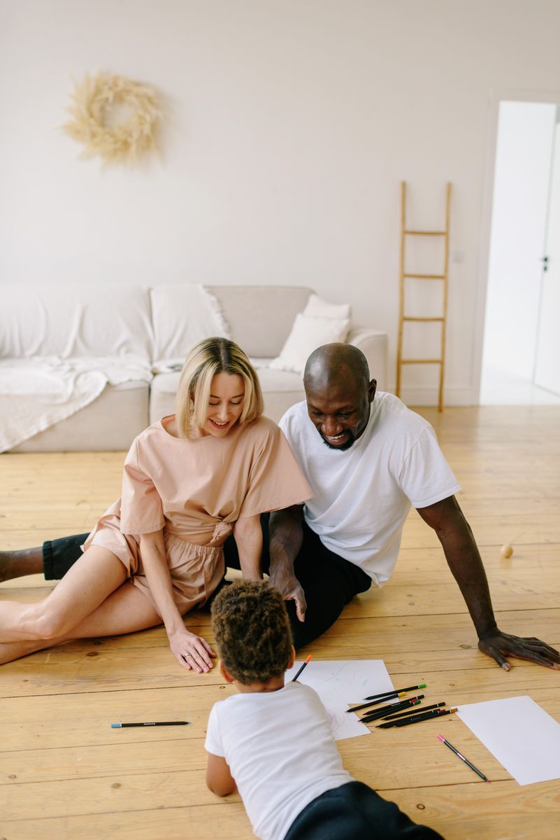 Happy family enjoying drawing together at home with art materials and colored pencils.